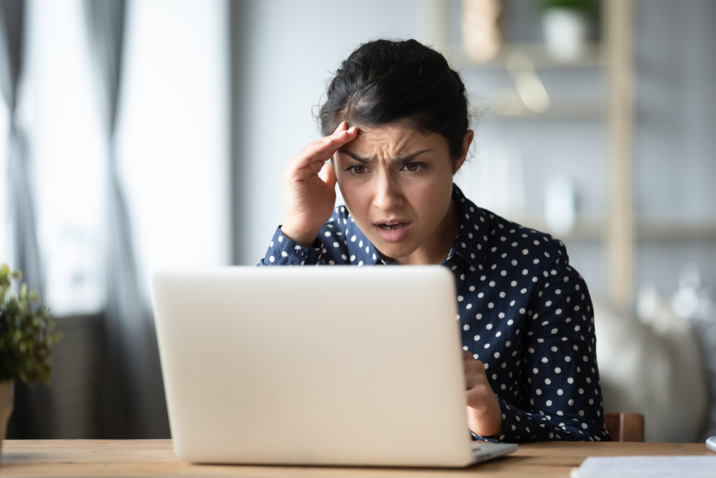 Woman looking at computer shocked at all of the security compliance requirements her company must follow